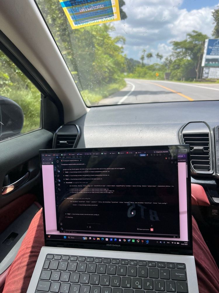 Laptop open with code on a car dashboard, tropical road ahead